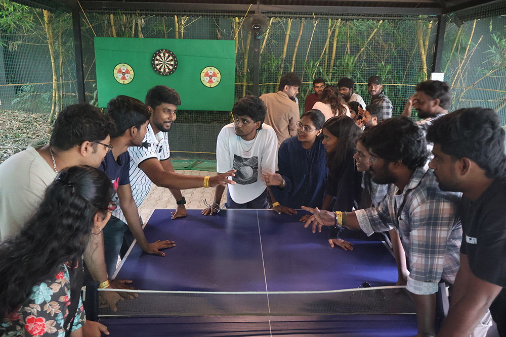 Colleagues crowded around a table tennis table during an offsite games session